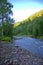 A shallow stony river winds through a beautiful morning forest