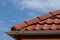 shallow zink eavestrough or gutter. red brown sandy textured modern concrete roof tiles in closeup