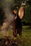 Shaman woman playing on shaman drum near large fire