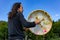 Shamanic male playing sacred drum with stick