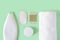 Shampoo, cotton pads, cotton buds wood stick, face cream and white terry towel on a pastel mint background. Purity, hygiene, and