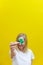 Shamrock in hand of young women in front of her face. Girl\\\'s face on yellow background. Selective focus