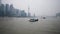 Shanghai, China - Feb. 21, 2019: cargo ships sailing in Huangpu river with Shanghai Bund skyscraper landscape and overcast sky