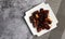 Shanghai-Style Red Braised Pork Belly or Hong Shao Rou on a white square  plate on a dark background