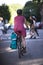 Shaped woman in red dress and boots rides bicycle with bag fastened to bike along street in urban city