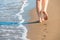 Shapely female legs leave footprints on a sand