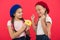Share sweet donut. Girls in beret hats hold glazed donut red background. Kids playful girls ready eat donut. Friendship