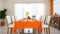 Shared Moments. White Chairs Encircle Long Table Draped in Vibrant Orange