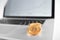 Sharp focus on golden bitcoins placed on silver laptop with blurred financial chart on its screen