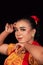 a Sharp gaze from an Indonesian woman with makeup on her face while wearing an orange dress and golden earrings