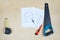 Sharp hacksaw, tape measure and knife on wooden surface, building tools next to blueprint