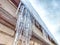 Sharp icicles from melted snow hanging from eaves of roof. Beautiful transparent icicles. Icicles on the eaves of the