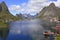 Sharp mountains, red huts and fishing boats reflected into the fjord in Reine