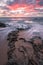 Sharp pink sunset over water movements on beach rocks in Kenting, Taiwan