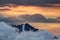 Sharp ridges above sea of clouds illuminated by rising red sun