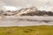 Sharp snowy peaks of Alps mountains above valley full of heavy fog, stormy weather