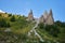 Sharp, towering rock formations pierce the sky above a vibrant green slope dotted with wildflowers