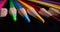 Sharpened tips of multicolored pencils on dark background