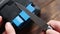 Sharpening a knife on an electric sharpener at home. The man`s hand drives the knife blade between the blue sharpeners, dust flies