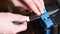 Sharpening a knife on an electric sharpener at home. The man`s hand drives the knife blade between the blue sharpeners, dust flies