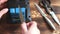 Sharpening a knife on an electric sharpener at home. The man`s hand drives the knife blade between the blue sharpeners, dust flies