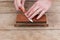 Sharpening the knife with a whetstone on a wooden background. Top view