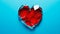 A shattered red heart against a stark blue background symbolizing heartbreak, broken relationship and emotional pain