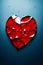 A shattered red heart against a stark blue background symbolizing heartbreak, broken relationship and emotional pain