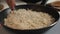 Shaving bits of parmesan cheese into hot risotto in a large stainless steel pan, close up video
