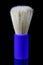 Shaving brush with bright blue plastic handle on black background