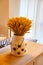 A sheaf or bouquet of dried wheat stalks stands in a vase on a wooden table against a light curtain background. Interior modern