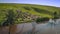 Sheep on a green meadow graze near a pond drone fly