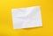 A sheet of crumpled white paper on a yellow background. Crumpled white paper background. Wrinkled leaf texture, top view.
