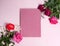 A sheet of dark pink paper, fresh roses on a light pink background.
