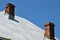 Sheet grey metal roof with two chimneys on a house