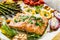 Sheet pan dinner - roasted salmon steak with asparagus, lemon ,rosemary, tomatoes, onion and garlic on cooking pan on wooden table