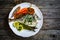 Sheet pan dinner - roasted whole sea bream with asparagus, carrots, lemon ,rosemary and garlic on cooking pan on wooden table