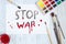 Sheet of paper with STOP WAR text, paintbrushes and watercolor p