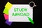 A sheet of paper with the words STUDY ABROAD, a cup of coffee, bright multi-colored stickers for notes and a green marker on a