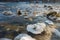 Sheets of ice crystals on rocks in flowing river Isar near Munich on cold foggy winter day