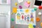 Sheets of paper, child`s drawing and magnets on refrigerator door in kitchen