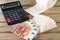 sheets and roll of toilet paper, calculator and euro money, on wooden background.