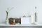 Shelf against white wall with decorative candle, glass, wood and rocks. Home plant in pot