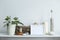 Shelf against white wall with decorative candle, glass, wood and rocks. Home plant in pot