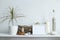 Shelf against white wall with decorative candle, glass, wood and rocks. Home plant in pot