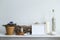 Shelf against white wall with decorative candle, glass, wood and rocks. Home plant in pot