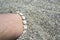 Shell ankle bracelet on half buried male leg