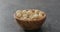 Shelled macadamia nuts in olive wood bowl on terrazzo surface