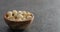 Shelled macadamia nuts in olive wood bowl on terrazzo surface