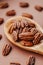 shelled pecans. Healthy fats. Pecan nuts close-up in a wooden spoon on a brown background.